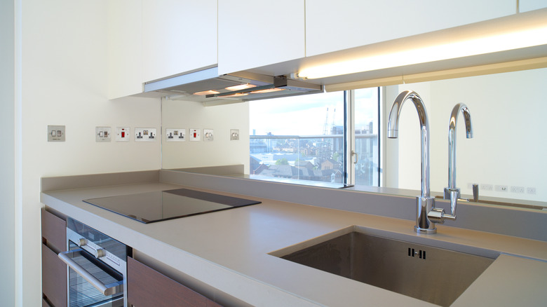 A fluorescent light illuminates a kitchen sink and countertop