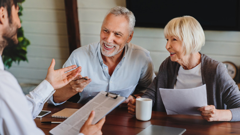 A smiling elderly couple signs home loan paperwork