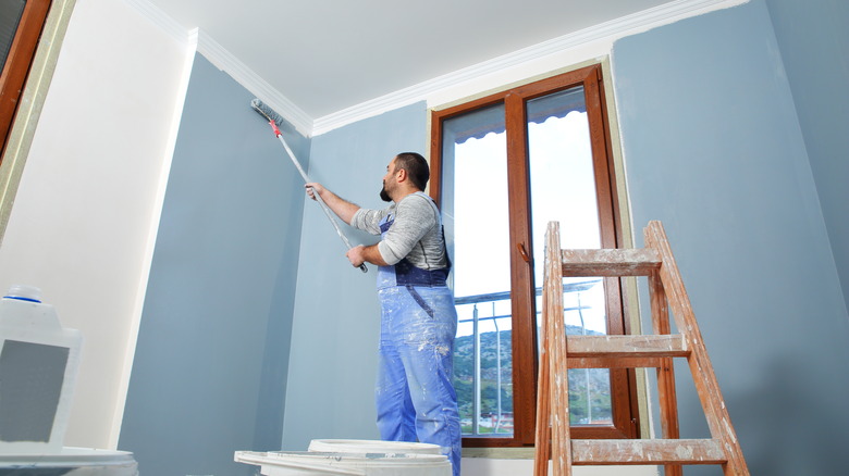 Painter painting drywall using roller
