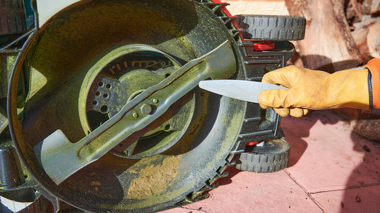 Someone using a sharpening stone on lawn mower blades