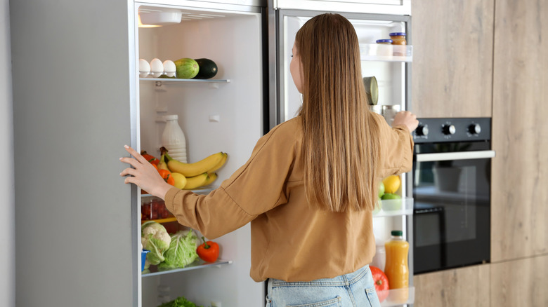 Woman standing in a kitchen with the fridge door open