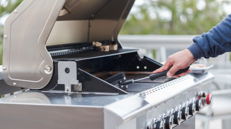 A person cleaning a gas grill