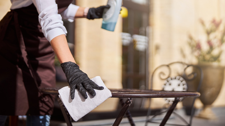 person wiping down metal table