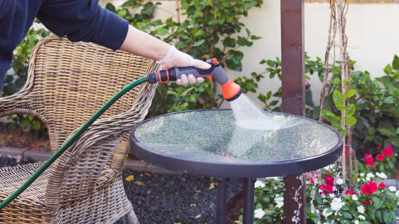 woman hosing outdoor metal table
