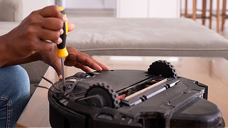 Close-up of a person putting robot vacuum back together