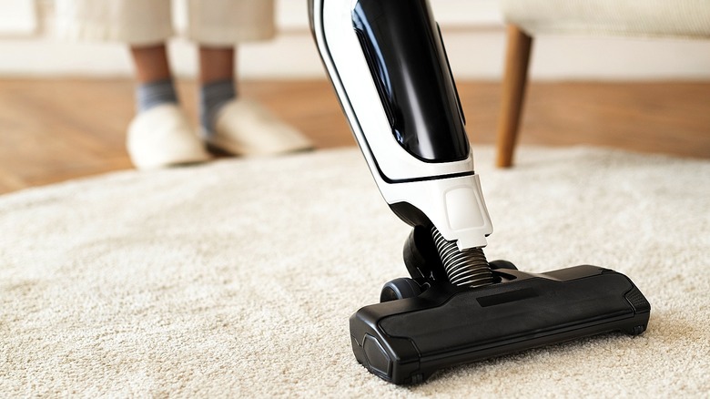 Close-up of a person vacuuming a cream rug