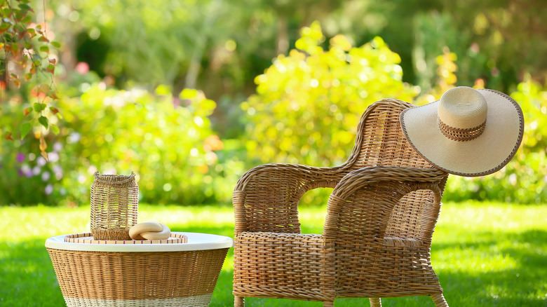 A wicker armchair and table in a sunny lawn
