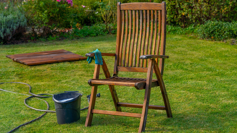Wood outdoor furniture being cleaned with cleaning supplies nearby