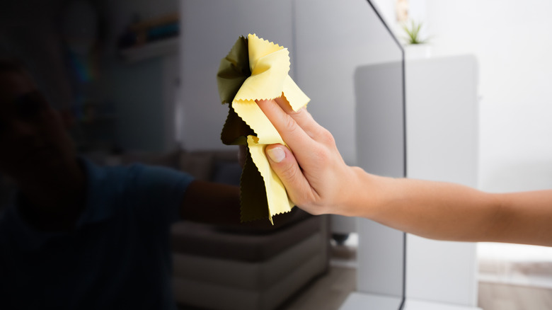 Close up of a person cleaning a TV screen with a microfiber cloth