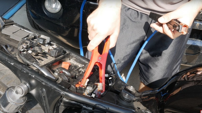 Man jump-starting a motorcycle from a car