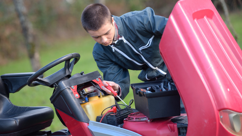 Man jump-starting a riding lawn mower