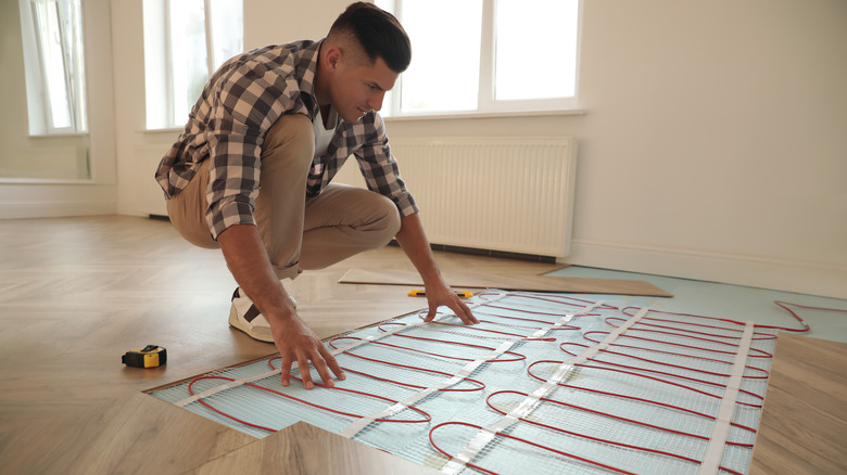 man installing heat coils/floor