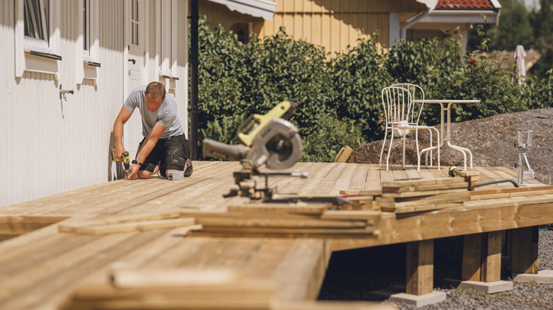 A man builds a new deck attached to a house