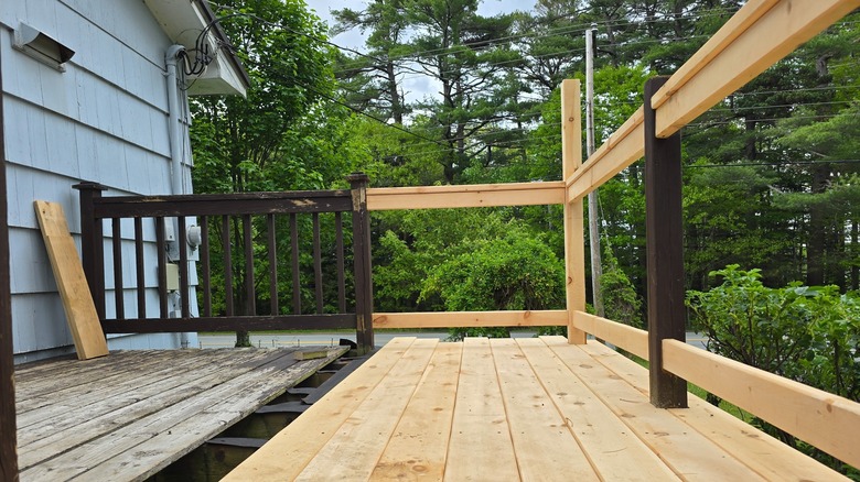 A rotting deck is partially repaired with new boards and railings