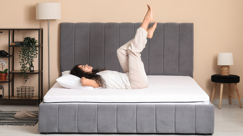 Happy woman lying on mattress with feet in the air