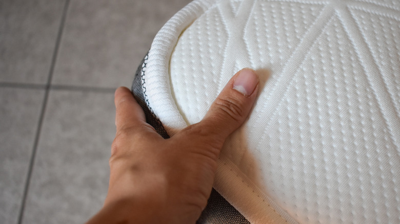 a man's hand holding onto the corner of a mattress