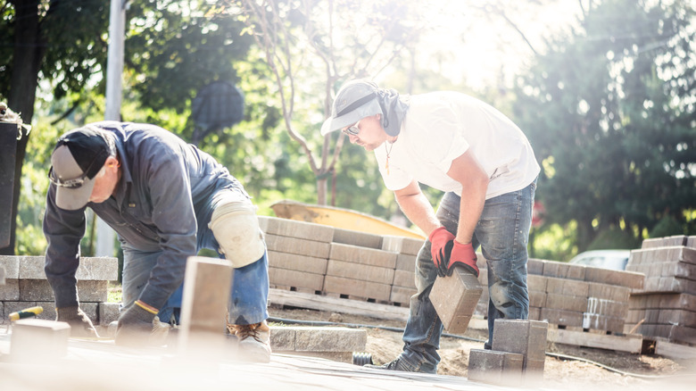 A father and son install paving stones together
