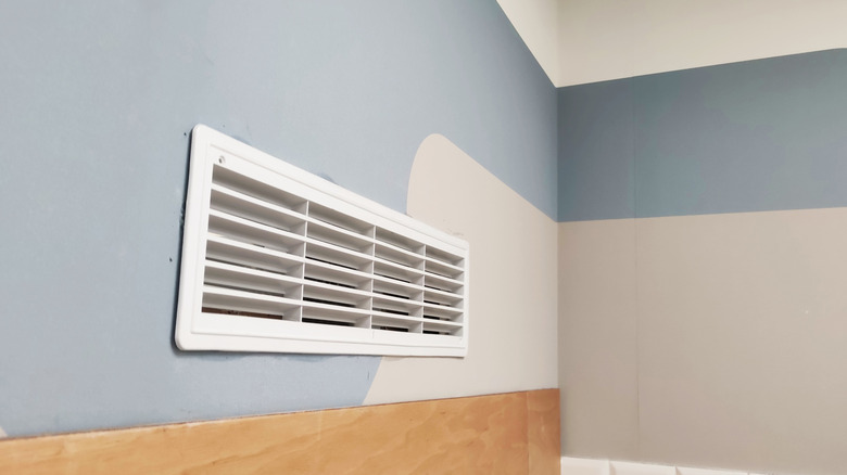 A white air vent on the blue and grey wall of a room
