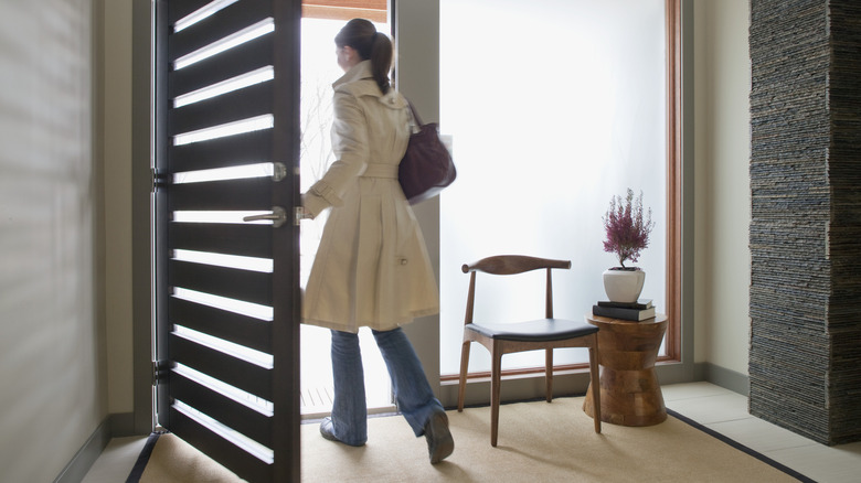 Woman walking out of the front door to her home