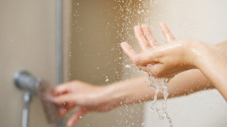Person sticking hand in shower water