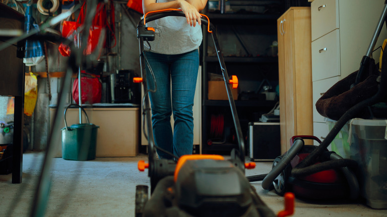 A person with a lawn mower in their garage