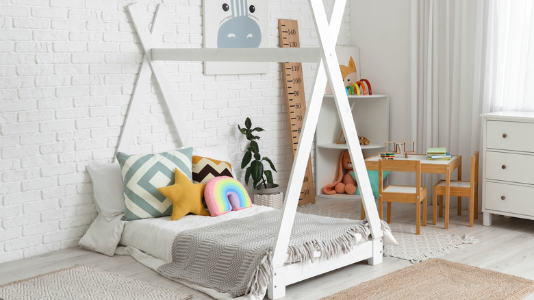 Floor bed with gray blanket and tent-like bed frame