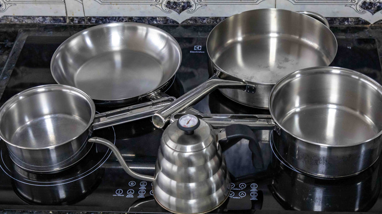 A stainless steel cookware set on top of an induction stove.