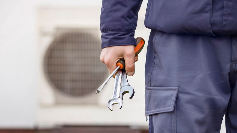 Man holding wrenches to install an electric heat pump
