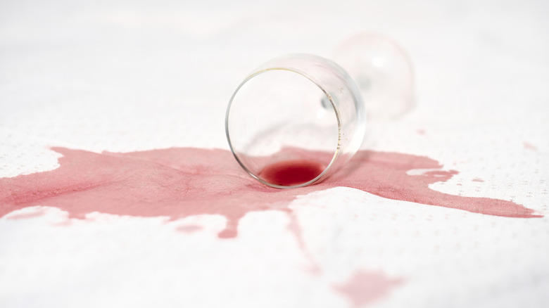 A glass of red wine spilled on white fabric