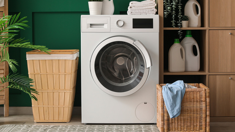 Washing machine, shelving unit, and laundry basket near green wall in room