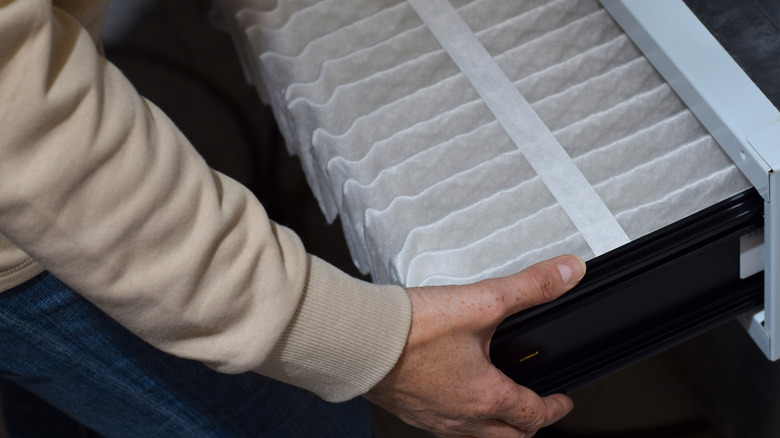 A person installing a pleated furnace filter