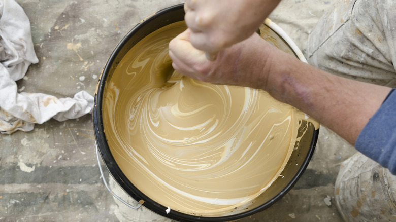 A person mixes pigment into a paint, changing its color