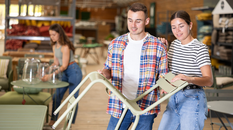 A couple looks at patio furniture inside a cozy store.