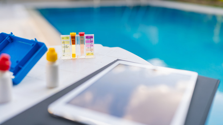 Swimming pool water quality checker kit with digital tablet by pool side.