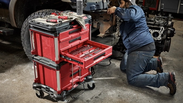 A mechanic uses the Milwaukee modular system with stacked 3-drawer toolboxes on wheels