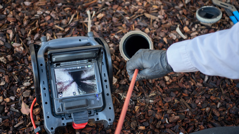 A person inspecting drain line with camera reel