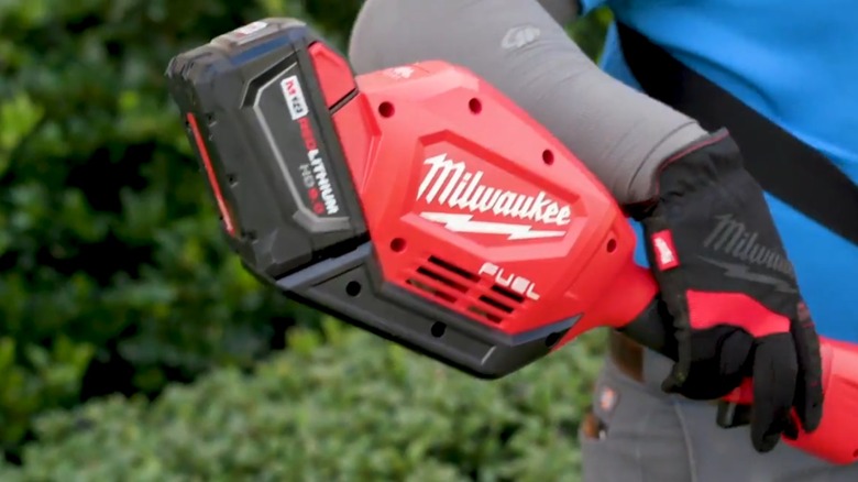 person using milwaukee m18 fuel string trimmer