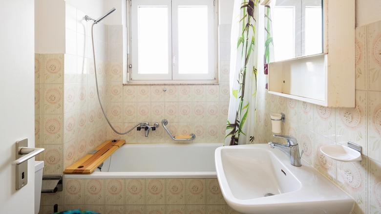 Vintage bathroom with green tiles and window.