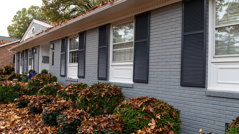Exterior of brick house, painted gray with dark gray shutters