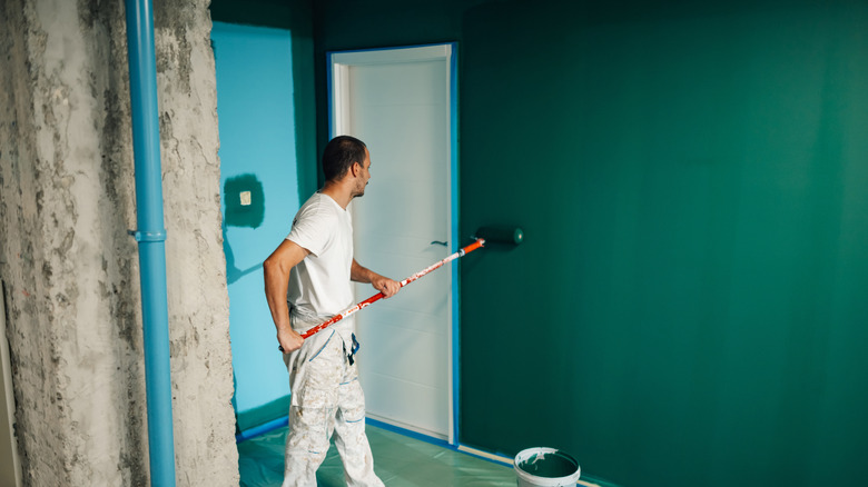 Painter using roller to paint walls