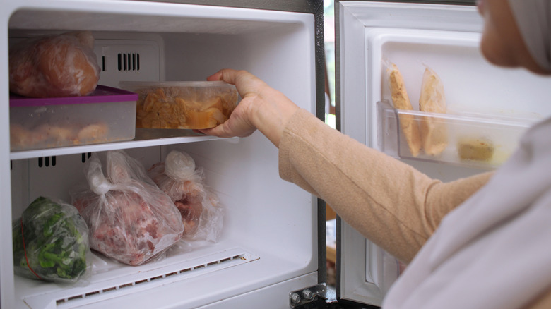 woman putting food items into her freezer