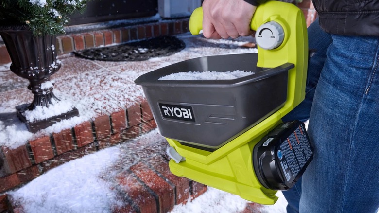 A person spreading ice melt onto walkway