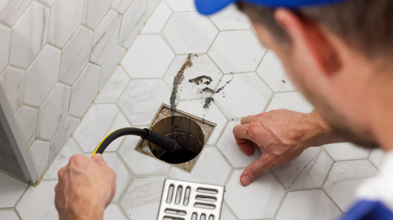 A plumber fixes a clogged shower drain