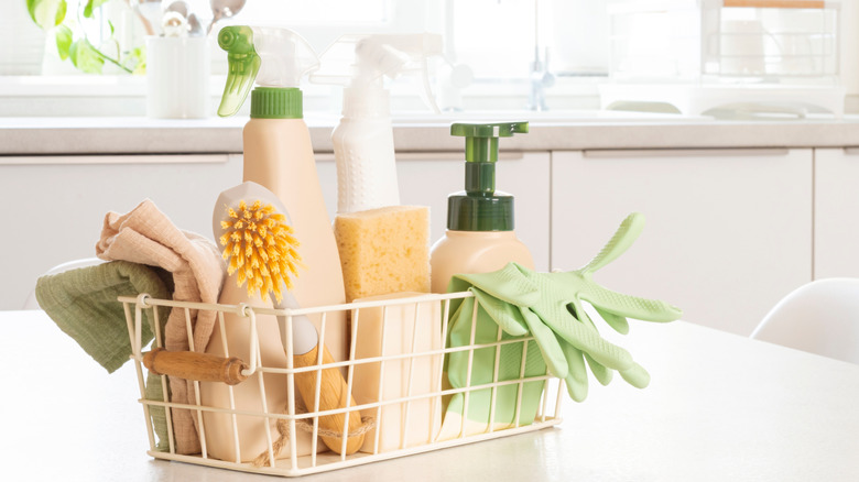 A basket full of cleaning products on a white kitchen counter