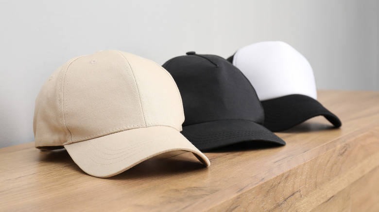 three baseball caps on a wooden shelf