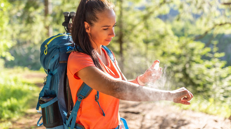 Person applying mosquito spray while hiking