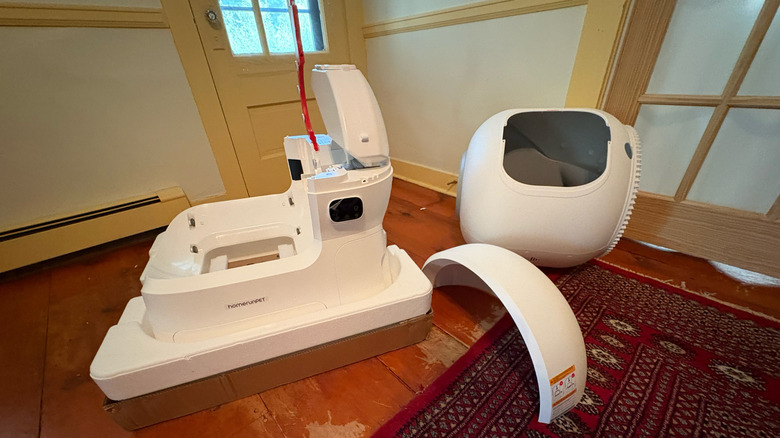 A homerunPET CS106 automatic litter box sits disassembled on a living room floor