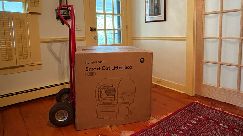 A homerunPET Smart Cat Litter Box CS106 box sits on a red hand truck