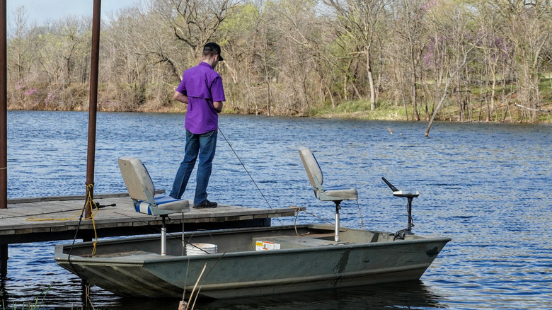 person fishing on dock on lake