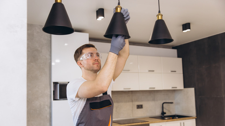 An electrician installing pendant lights in a kitchen